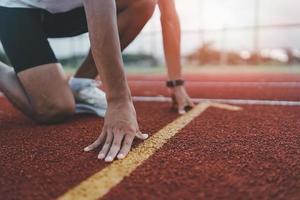 hände läufer startbereit zum runthlete sportman training laufen morgens auf der spur im stadion. läufermann, der weiße weste trägt, um das laufen zu üben, bereite sich auf das wettkampfrennen vor. foto