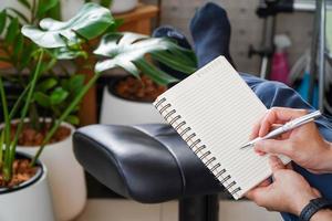 mann sitzt und ruht sich mit einem stift aus, um ein notebook zu schreiben. geschäfts- und bildungskonzept. foto