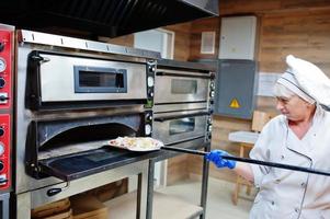 Köchin bereitet Pizza in der Restaurantküche zu. foto