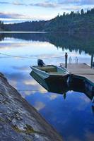 Wolkenreflexion auf ruhigem See mit Bootssteg foto