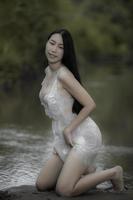 porträt einer sexy asiatischen frau am wasserfall, die sich am fluss frisch fühlt, die thailändische frau entspannt sich auf dem land foto