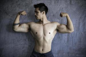 porträt des asiatischen mannes großer muskel im fitnessstudio, thailänder, training für gute gesunde, körpergewichtstraining, fitness im fitnessstudio-konzept foto