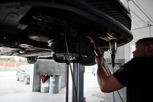 Thema Autoreparatur und -wartung. Mechaniker in Uniform, der im Autoservice arbeitet. foto