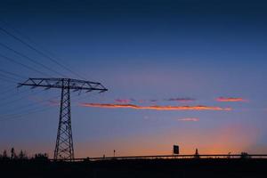 Strommast und Stromleitungen bei Sonnenuntergang