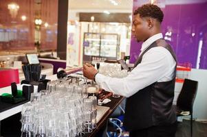 Afroamerikanischer Barkeeper an der Bar, der im Pub frisches Bier vom Fass in das Glas gießt. foto