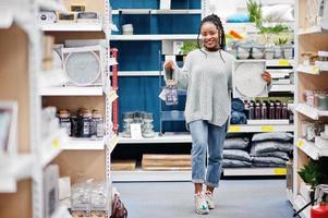 afrikanische frau, die uhr für ihre wohnung in einem modernen einrichtungsgeschäft wählt. foto