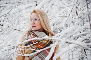 Porträt eines blonden Mädchens mit Brille, rotem Pelzmantel und Schal am Wintertag. foto