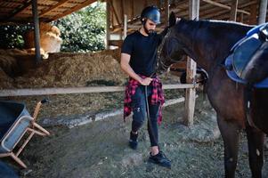 Arabischer Mann mit hohem Bart in schwarzem Helm mit arabischem Pferd. foto