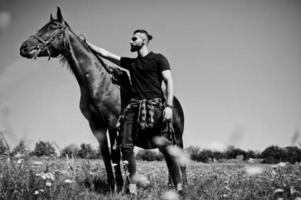 arabischer Mann mit hohem Bart in Schwarz mit arabischem Pferd. foto