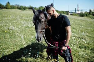 arabischer Mann mit hohem Bart in Schwarz mit arabischem Pferd. foto