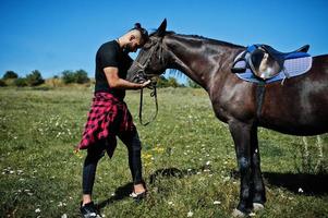 arabischer Mann mit hohem Bart in Schwarz mit arabischem Pferd. foto