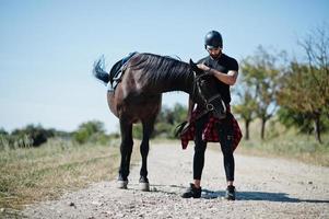 Arabischer Mann mit hohem Bart in schwarzem Helm mit arabischem Pferd. foto