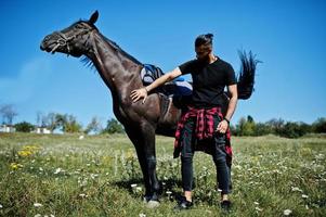 arabischer Mann mit hohem Bart in Schwarz mit arabischem Pferd. foto