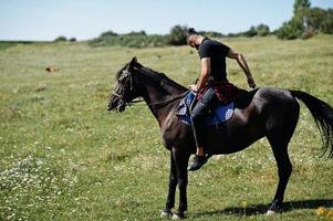 arabischer Mann mit hohem Bart trägt schwarzes arabisches Pferd. foto