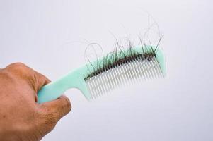 grüner Kammgriff schwarze Haare fallendes Haarpflegekonzept, Werbung für Krebs, Chemotherapie, Shampoo und Conditioner foto