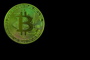 grüne einzelne bitcoin aus der kryptowährung während des steigenden marktes auf schwarzer rückseite foto