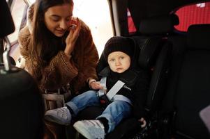 junge Mutter und Kind im Auto. Kindersitz auf Stuhl. Fahrsicherheitskonzept. foto