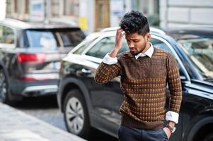 Porträt einer jungen, stilvollen indischen Mann-Model-Pose auf der Straße gegen ein SUV-Auto. foto