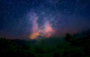 Milchstraße und rosa Licht in den Bergen. nacht bunte landschaft. Sternenhimmel mit Hügeln im Sommer. schönes Universum. Weltraumhintergrund mit Galaxie. Reisehintergrund foto