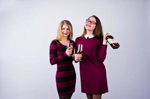 Zwei attraktive Freundinnen in lila Kleidern trinken Sekt oder Champagner im Studio. foto