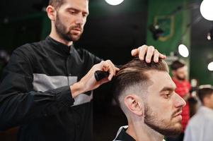 hübscher bärtiger mann im friseursalon, friseur bei der arbeit. foto