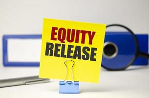 Word Equity Release auf gelbem Aufkleber und blauem Ordner foto