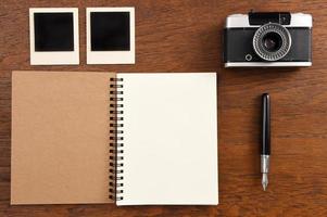 leeres Notizbuch mit Stift, Bilderrahmen und Kamera