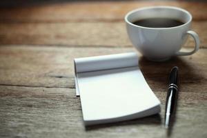 Öffne ein leeres weißes Notizbuch, einen Stift und eine Tasse Kaffee