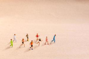 Miniaturmenschen, die beim Laufen in einer Gruppe am Strand trainieren foto