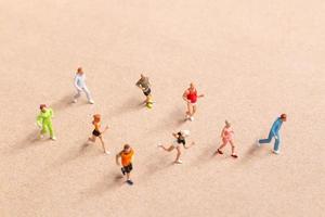 Miniaturmenschen, die beim Laufen in einer Gruppe am Strand trainieren foto