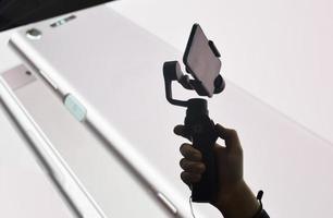 eine Silhouette der Hand eines Mannes, die ein Mobiltelefon auf einem Gimbal hält foto