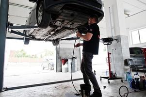 Thema Autoreparatur und -wartung. Mechaniker in Uniform, der im Autoservice arbeitet. foto