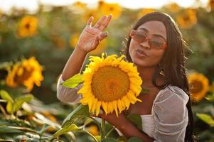 hübsche junge schwarze Frau tragen Sommerkleid Pose in einem Sonnenblumenfeld. foto