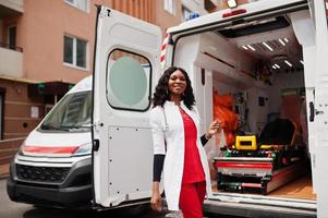 Afroamerikanische Sanitäterin, die vor einem Krankenwagen steht. foto