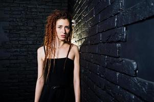 Studio-Shooting von Mädchen in Schwarz mit Dreads auf Backsteinhintergrund. foto