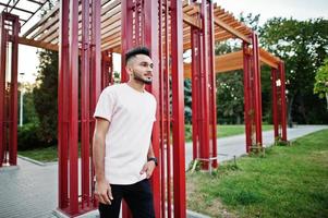 stilvoller indischer bartmann am rosa t-shirt. Indien-Model posierte unter rotem Bogen im Park der Stadt. foto