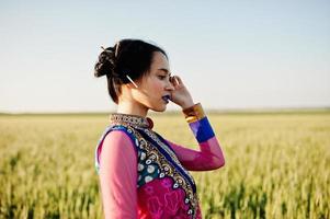 zartes indisches mädchen im saree, mit violetten lippen, die bei sonnenuntergang auf dem feld posierten. modisches Indien-Modell. foto