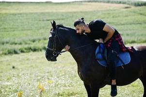 arabischer Mann mit hohem Bart trägt schwarzes arabisches Pferd. foto