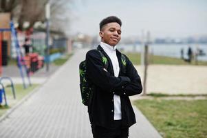 junger tausendjähriger afrikanischer junge, der in der stadt spaziert. glücklicher schwarzer Mann mit Marihuana-Rucksack. generation z-konzept. foto