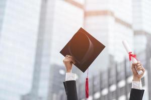 Absolventen feiern ihren Abschluss. Glücksgefühle halten Showhut und Diplomurkunde im Schulgebäude im Hintergrund. glückwunschausbildung während des beginns des universitätsabschlusses. foto