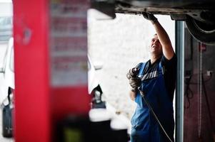 Thema Autoreparatur und -wartung. Mechaniker in Uniform, der im Autoservice arbeitet. foto