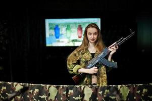 Mädchen mit Maschinengewehr an den Händen auf dem Schießstand. foto