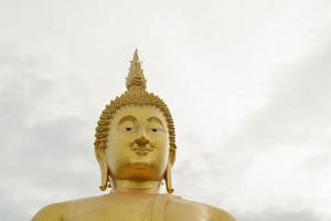 das gesicht der goldenen großen buddha-statue im wat muang in der provinz ang thong, thailand. foto