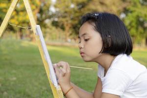 Asiatisches kleines Mädchen, das im Park malt foto