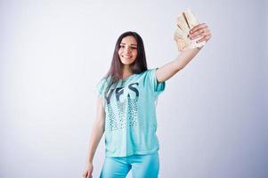 Porträt eines attraktiven Mädchens in blauem oder türkisfarbenem T-Shirt und Hose, das mit viel Geld in der Hand posiert. foto