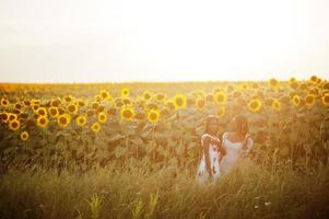 zwei hübsche junge schwarze Freunde Frau tragen Sommerkleid Pose in einem Sonnenblumenfeld. foto