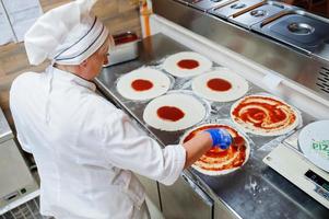 Köchin bereitet Pizza in der Restaurantküche zu. foto