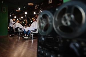 hübscher bärtiger mann im friseursalon, friseur bei der arbeit. foto