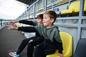 Zwei Brüder unterstützen ihre Lieblingsmannschaft und sitzen auf dem Sportpodium im Stadion. foto