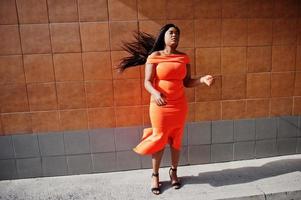 afroamerikanerfrau modell xxl im orangefarbenen kleid. foto